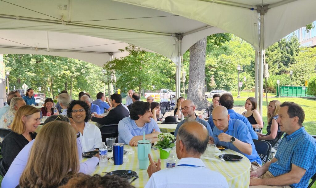 A group of people are gathering under a large tent for a picnic.