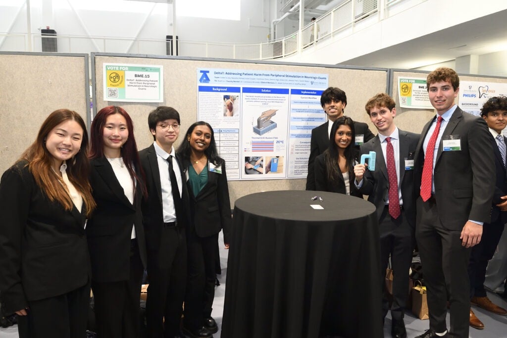 A group of student pose for a photo in front of their poster.